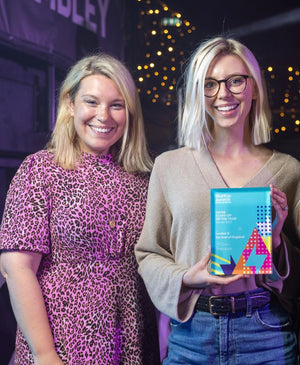 A photo of founders Laura & Laura holding an award at a ceremony, after winning Best Drinks Startup at the National Startup Awards. 